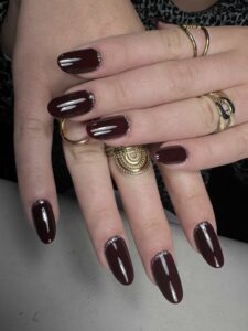 Manucure bordeaux avec paillettes argentées sur le bord libre des ongles