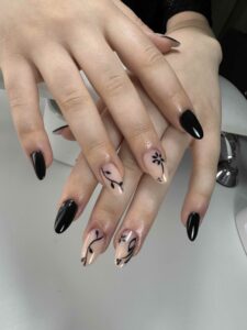 Détail d'une manucure noire et nude élégante avec fleurs noires